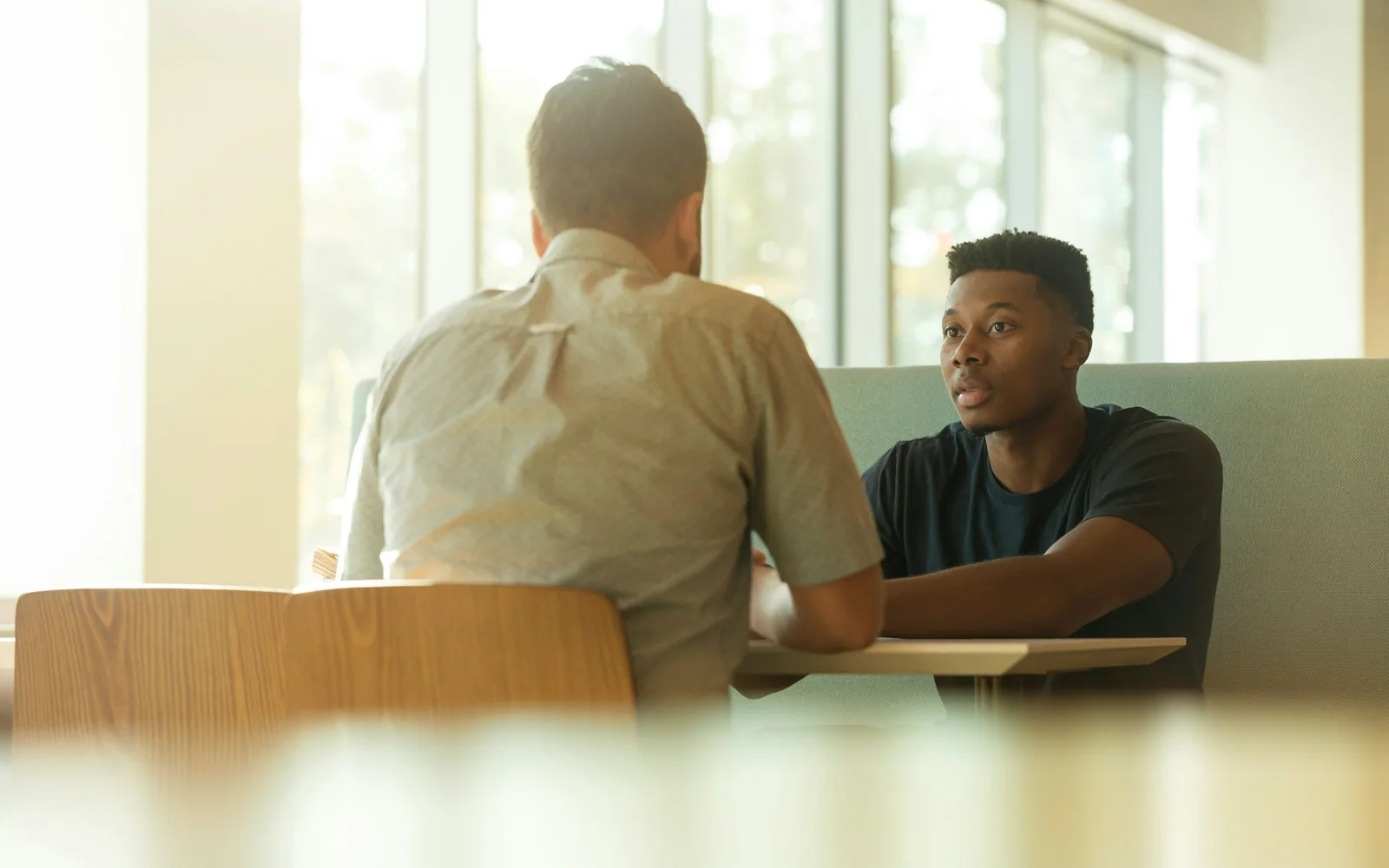 Dos profesionales conversan frente a frente en una mesa
