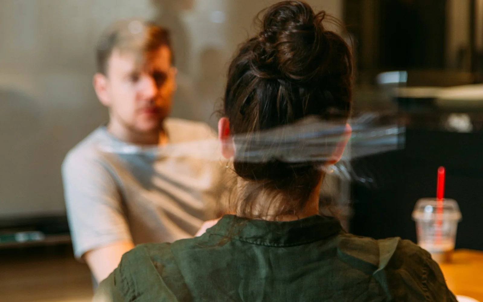 Dos personas conversan en una sala de trabajo vista a través de un cristal