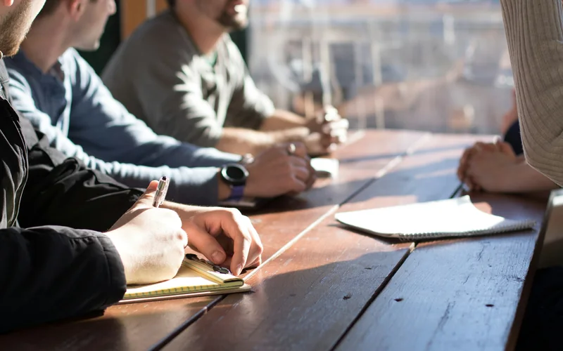 Varias personas toman notas alrededor de una mesa de trabajo